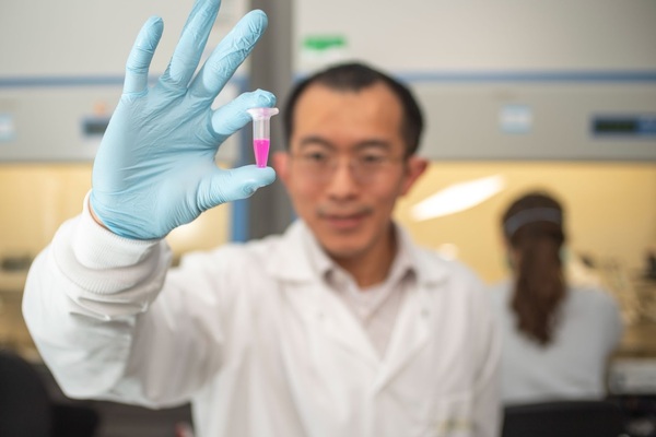 Donny Hanjaya Putra Assistant Professor Of Aerospace And Mechanical Engineering Holds A Vial Of Specially Engineered Nanoparticle Backpacks